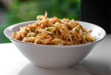 Eine Schüssel mit frisch zubereitetem nepalesischen Krautsalat, bekannt als Banda ko Sadheko Achar. Fein geschnittener Weißkohl ist mit einer rötlichen, würzigen Tomatensoße und sichtbaren Gewürzen wie schwarzen Senfsamen vermischt.