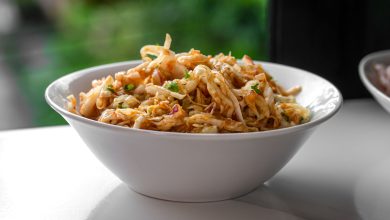 Eine Schüssel mit frisch zubereitetem nepalesischen Krautsalat, bekannt als Banda ko Sadheko Achar. Fein geschnittener Weißkohl ist mit einer rötlichen, würzigen Tomatensoße und sichtbaren Gewürzen wie schwarzen Senfsamen vermischt.